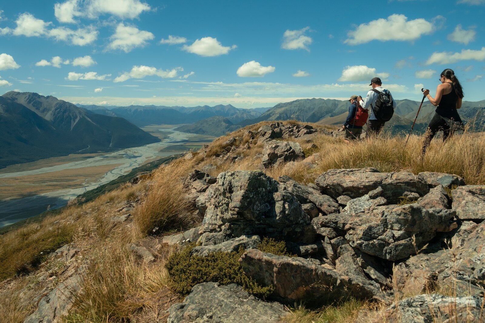 Two hikers on a mountain ridge overlooking a valley.